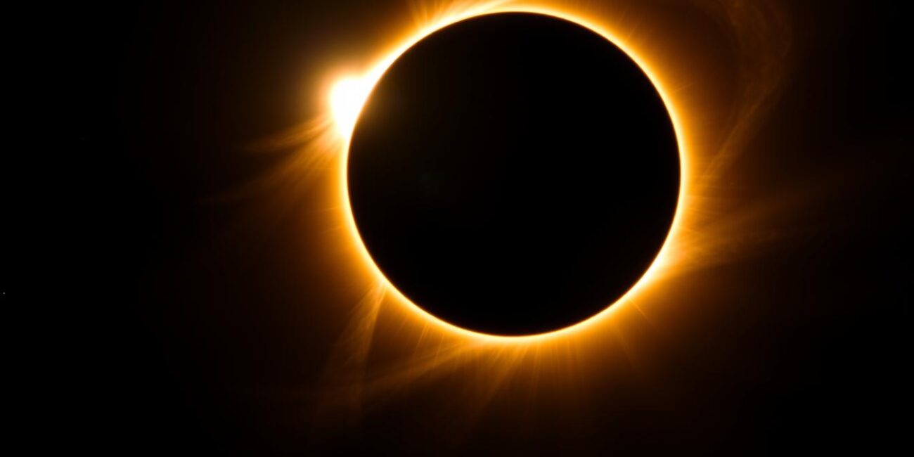 Total solar eclipse with corona visible against dark sky, natural phenomena tourism
